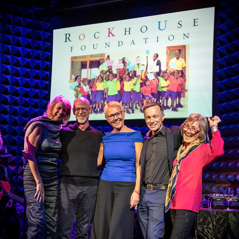 Five people on stage at a Foundation benefit, in front of a projected Rockhouse Foundation title card