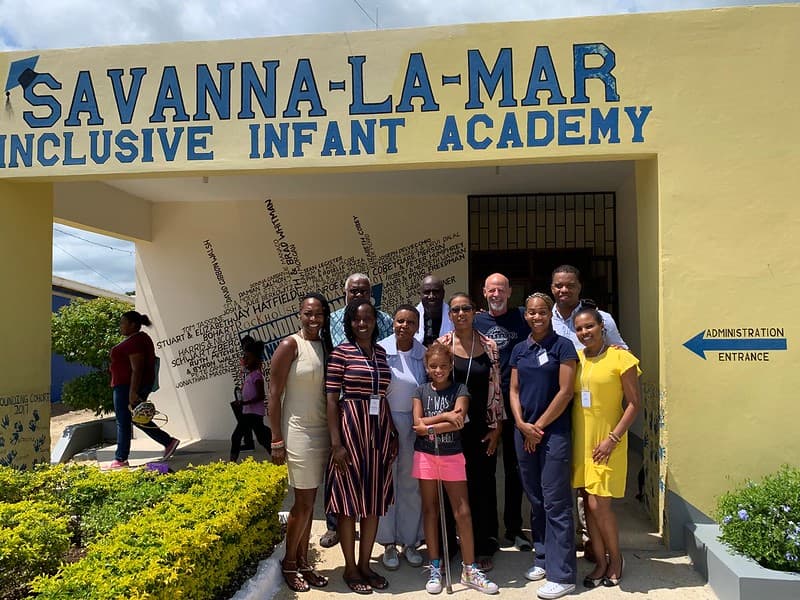 Adults and one child gathered outside the administration entrance of the Savanna-la-Mar Inclusive Infant Academy