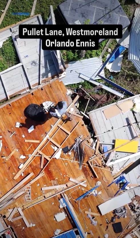 An aerial view of a house at Pullet Lane, Westmoreland, its roof torn off by Hurricane Melissa, with a man standing among the debris